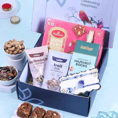 FlowerAura Premium Raksha Bandhan Hamper Include Bhaiya Bhabhi Evil Eye Rakhi, Trail Mix, 250g Dodha Burfi, Hazelnut Rocks, Kalimirch Cashew & Roli Chawal In Box- Rakhi For Bhaiya Bhabhi & Cousins